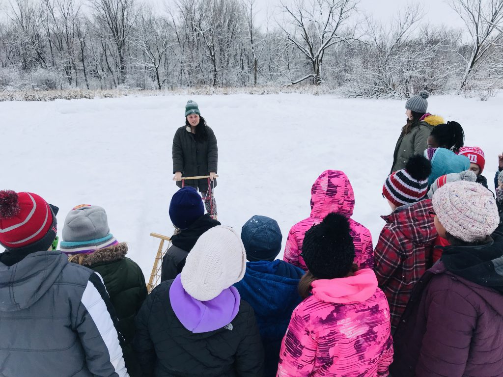 Dodge Nature Center Naturalist Fellow Ashley Johnson introduces elementary school students to kicksledding on the Farm Pond.