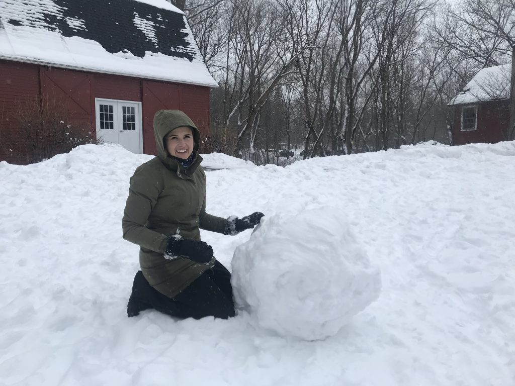 Dodge Nature Center Naturalist Fellow Julia Pedersen preps the base of a snowman.