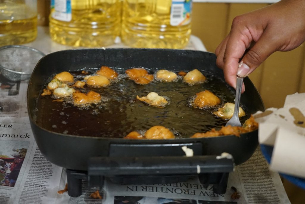 Golden and crispy battered dandelions bubble in frying oil. 