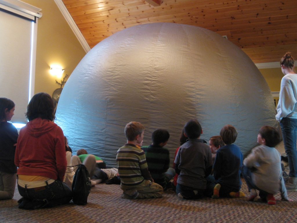 Students sit and wait patiently to enter the inflated Star Lab.